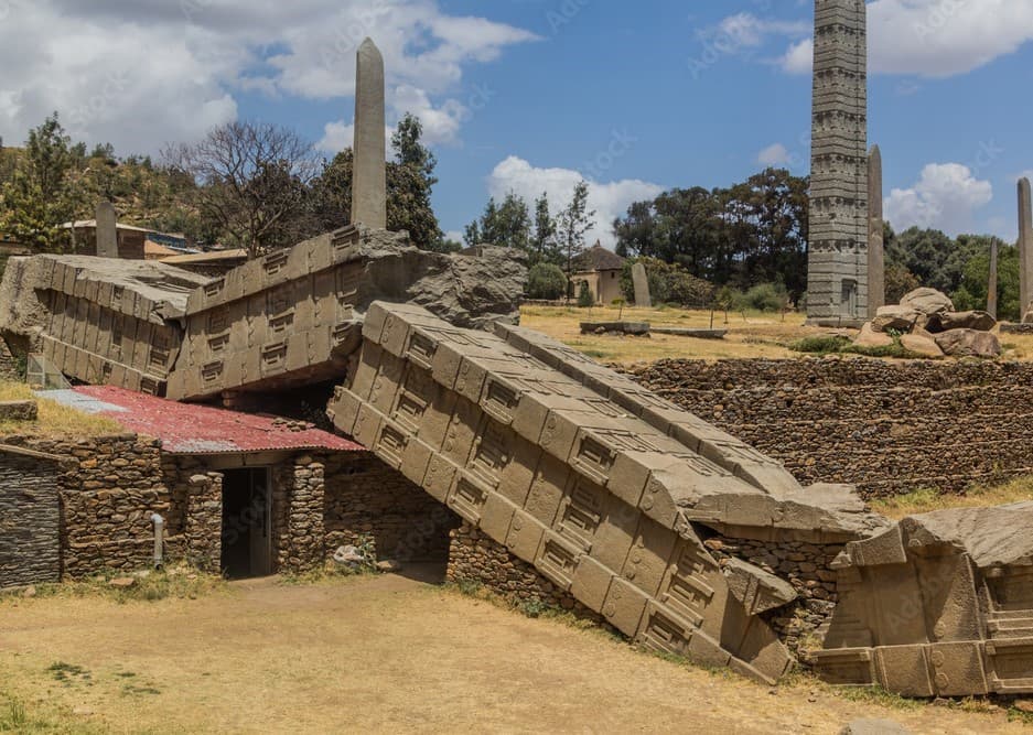 Tall, intricately carved Axum obelisk with detailed architectural features and vertical grooves simulating windows and doors